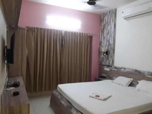 a bedroom with a white bed and a brown curtain at hotel sagnik in Murshidābād