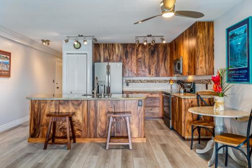 a kitchen with wooden cabinets and a counter with stools at The Sea Village #1302 in Kailua-Kona