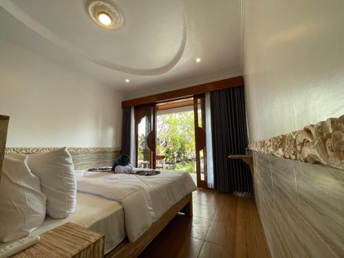 a bedroom with a bed and a large window at Mikuk Cottages Canggu in Canggu