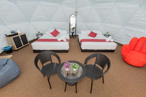 a room with two beds and chairs in a tent at Glamz Hills in Cameron Highlands