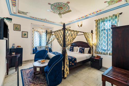 a bedroom with a canopy bed and a chair at Kaner Bagh A Heritage Boutique Hotel in Udaipur