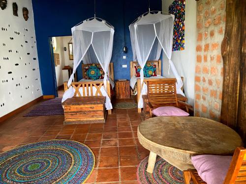 a room with two beds and a table in it at Chameleon Hill Forest Lodge in Bwindi