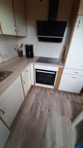 a kitchen with white cabinets and a wooden floor at Ferienwohnung Langfeld in Kronsgaard