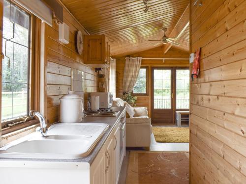 uma cozinha num chalé de madeira com um lavatório em Llama Lodge em Otterford