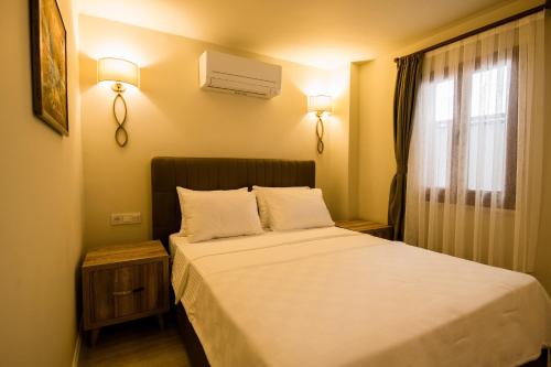 niewielka sypialnia z łóżkiem z białą pościelą i oknem w obiekcie KALAMAKİ FLATS w Kaş