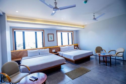 pokój hotelowy z 2 łóżkami, krzesłami i oknami w obiekcie HOTEL OM w mieście Somnath