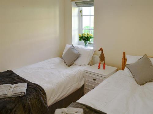a bedroom with two beds and a vase of flowers at Coots Nest in Stalham