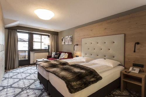 ein Hotelzimmer mit einem großen Bett mit einer Decke darauf in der Unterkunft Hotel Valentin in Sölden