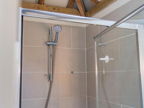 a shower with a glass door in a bathroom at Shepherds Cottage in Pett