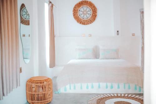 a white bedroom with a bed and a wooden stool at VILLA LA ISLA BONITA walking distance to the beach in Gili Air