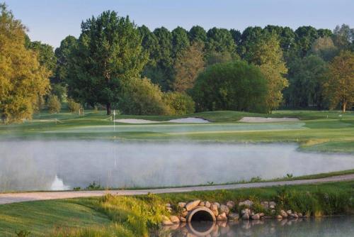 a view of a golf course with a pond at Hotel Gut Kaden in Alveslohe
