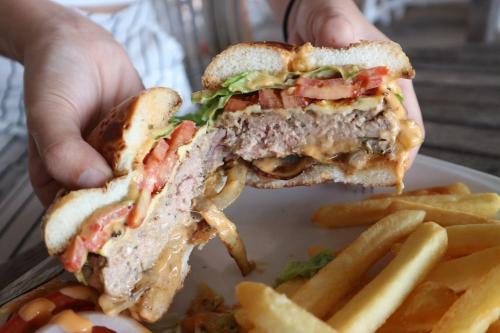 Una persona sosteniendo un sándwich y papas fritas en un plato. en Baanboonpetch Resort, en Ban Phlong Takhe
