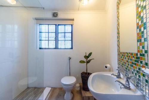a bathroom with a sink and a toilet and a window at Surburban Bliss - Claremont in Cape Town