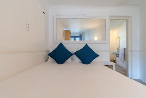 a bedroom with a white bed with blue pillows at Surburban Bliss - Claremont in Cape Town