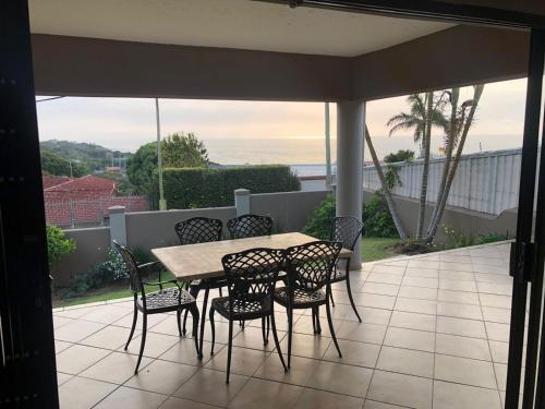 a table and chairs on a patio with a view of the ocean at Sanlou in Port Shepstone