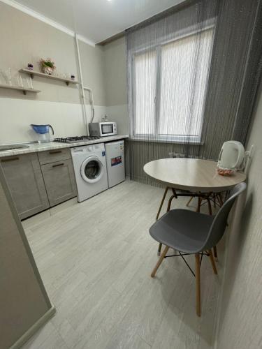 eine Küche mit einem Tisch, einem Tisch und einer Waschmaschine in der Unterkunft VIP квартира центр in Oral