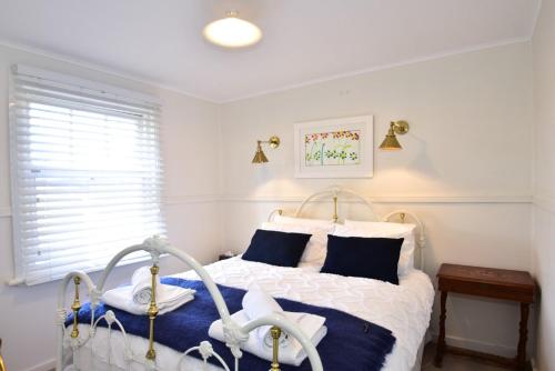 um quarto com uma cama branca e almofadas azuis em Farm Cottage close to Dubbo em Dubbo