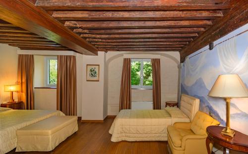 a bedroom with two beds and a couch and two windows at Hotel Villa La Principessa in Lucca