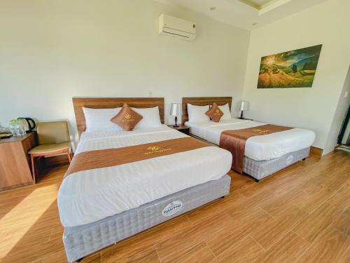 a hotel room with two beds and a desk at Emopea Moc Chau in Mộc Châu