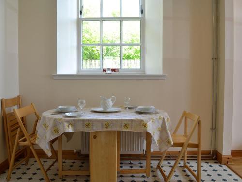 uma mesa com uma toalha de mesa num quarto com uma janela em Grey Granite em Arbuthnott