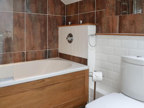 a bathroom with a tub and a toilet at Thwaite Cottage in Sigglesthorne