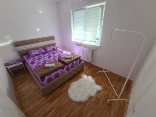 a bedroom with a purple bed and a window at Apartman CRYSTAL in Brčko