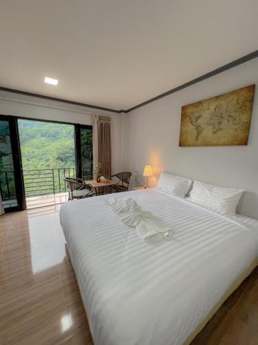 a bedroom with a large white bed and a balcony at Yamee Homestay Cafe in Ban Pha Mi
