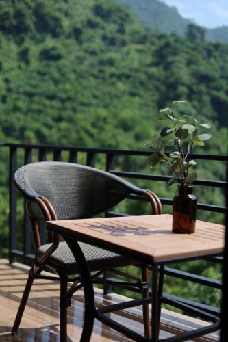 a wooden table and a chair with a plant on a porch at Yamee Homestay Cafe in Ban Pha Mi