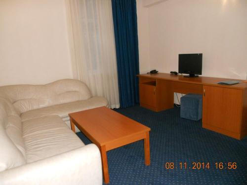 a living room with a couch and a desk with a television at Family Hotel Helios in Sevlievo