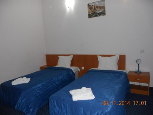 two beds in a hotel room with towels on them at Family Hotel Helios in Sevlievo