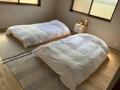 a bedroom with two beds and a mirror and a window at ゆったりとした時間を過ごせる一棟貸切の別荘　たけしま in Naruto
