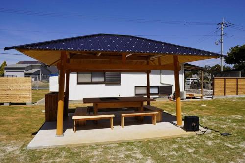 a gazebo with a picnic table and a bench at ゆったりとした時間を過ごせる一棟貸切の別荘　たけしま in Naruto