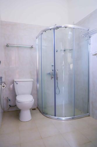 a bathroom with a toilet and a glass shower at Ilamperuma Bungalow in Weligama