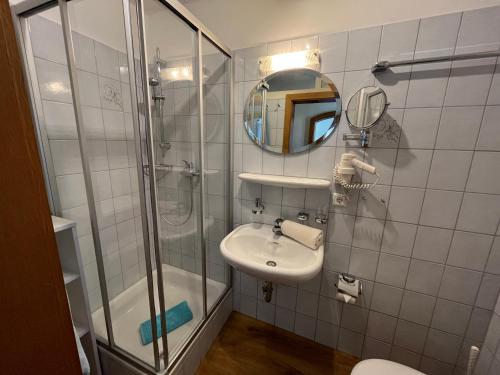 a bathroom with a shower and a sink and a mirror at Gasthof - Pension - Adler in Weiler-Simmerberg