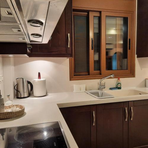 a kitchen with wooden cabinets and a sink at Family Comfortable Spacious Apartment in Heraklio