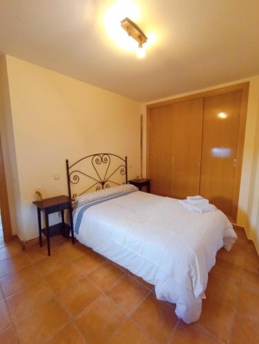 1 dormitorio con cama blanca y armario de madera en El Rincón del Sanabrés, Hermana Menor, petfriendly en Rascafría