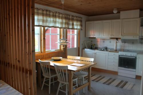a kitchen with a wooden table and chairs and a table and a kitchen at Backs Semesterby in Duved