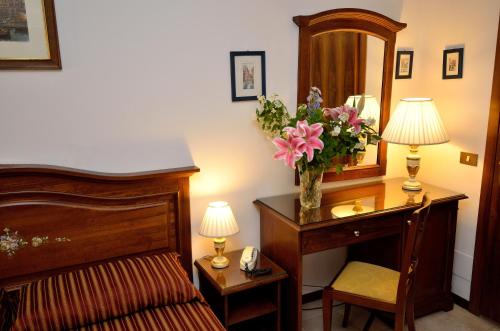 a bedroom with a bed and a desk with a vase of flowers at Hotel Orion in Venice