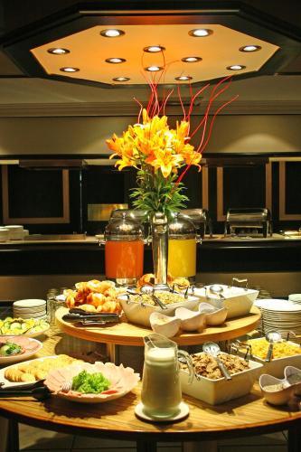 a table with plates of food and a vase of flowers at Oudtshoorn Inn Hotel in Oudtshoorn