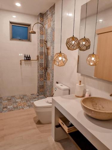 a bathroom with a toilet and a sink and lights at Wayla Villa@Maikhaobeach in Mai Khao Beach