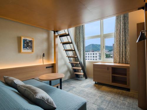 a bedroom with a bed with a ladder and a window at GRIDS PREMIUM HOTEL OTARU in Otaru