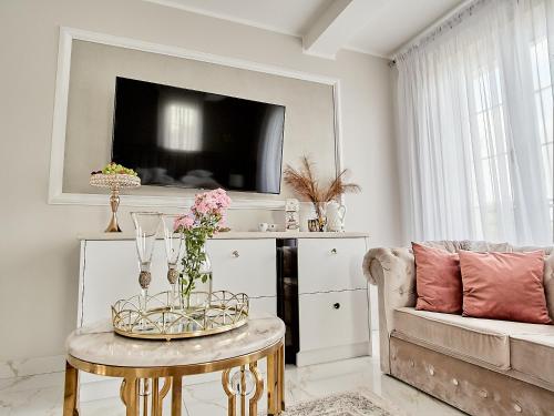 a living room with a couch and a table with flowers on it at La Rose Residence in Mikołajki