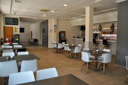 un restaurante con mesas y sillas blancas y un bar en Hotel Reigosa, en Pontevedra