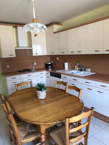 une cuisine avec une table en bois et quelques chaises dans l'établissement Maison Le Bel Air à 3km du virage de Mulsanne 9 couchages, à Ruaudin