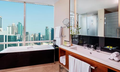 InterContinental Doha The City, an IHG Hotel في الدوحة: حمام مع حوض استحمام و نافذة كبيرة