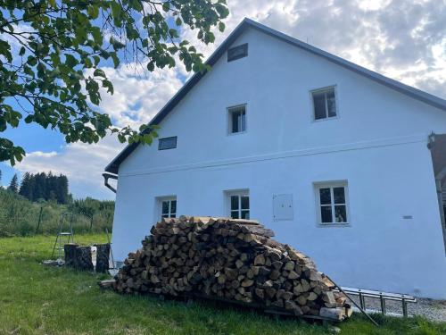 a pile of firewood in front of a white house at Romantická chalupa s krbem in Hořice na Šumavě