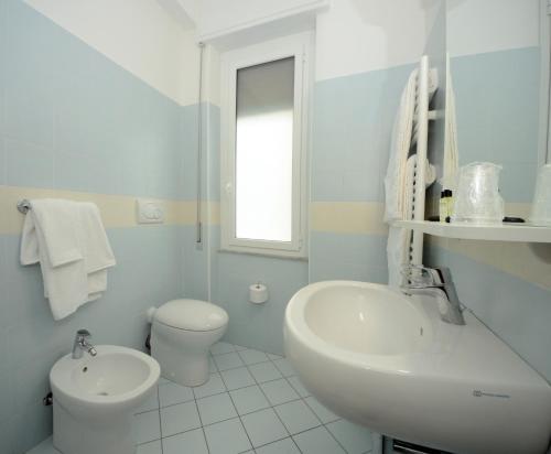 La salle de bains blanche est pourvue d'un lavabo et de toilettes. dans l'établissement Hotel Lido Mazzini, à Loano