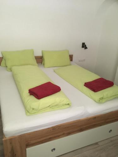 two beds with yellow and red pillows on them at Pension Steiner, 6143 Matrei am Brenner!!Check-in between 15 - 21 o'clock!! No breakfast in Mühlbachl