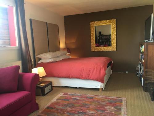 una camera con letto rosso e divano di La casa rossa a Saint-Riquier-ès-Plains