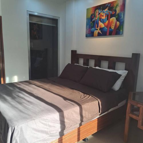 a bed in a bedroom with a painting on the wall at GIARDINO ROMANTICO in Dumaguete